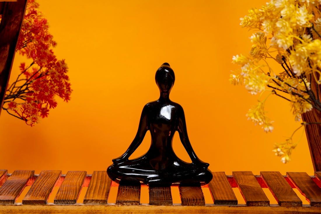a black buddha statue sitting on top of a wooden table
