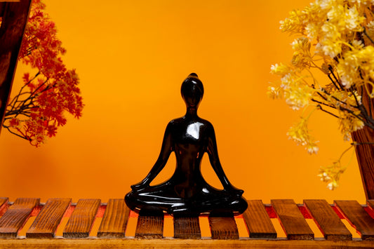 a black buddha statue sitting on top of a wooden table