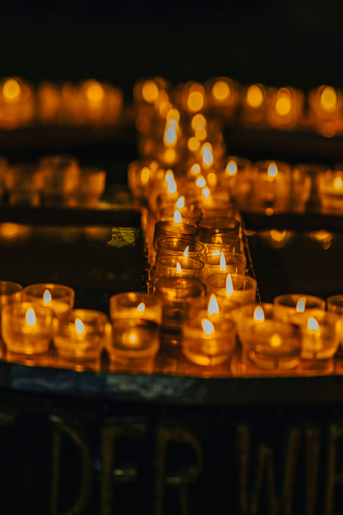 rows of lit candles sitting on top of a table