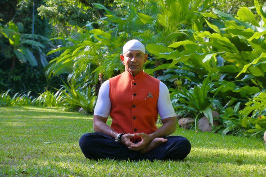 A man in a red vest sitting in the grass